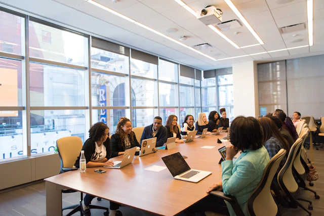 Professionals collaborating around a meeting table with laptops