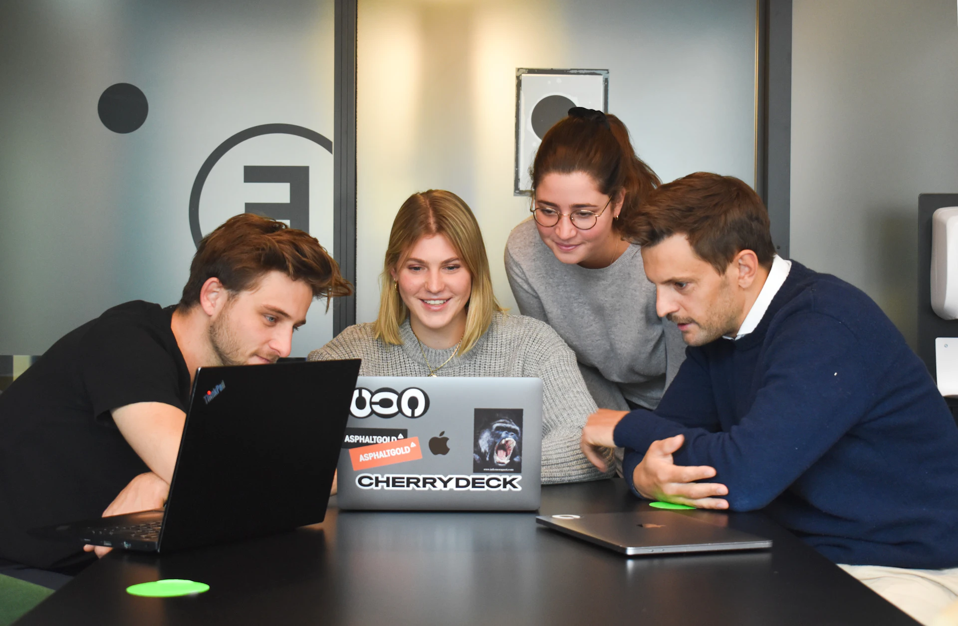 Colleagues reviewing work together around a laptop
