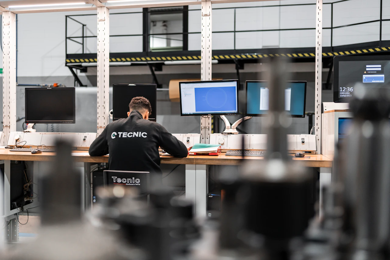 Engineer reviewing mechanical components on multiple workstation screens